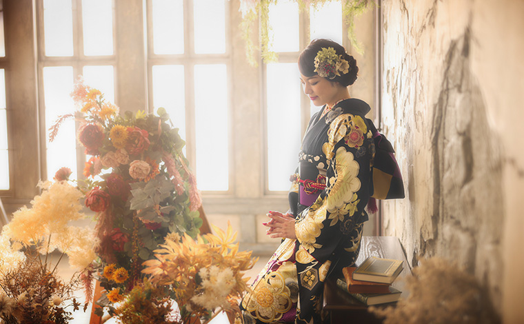 黒の振袖を着た女性の着付けをしている様子